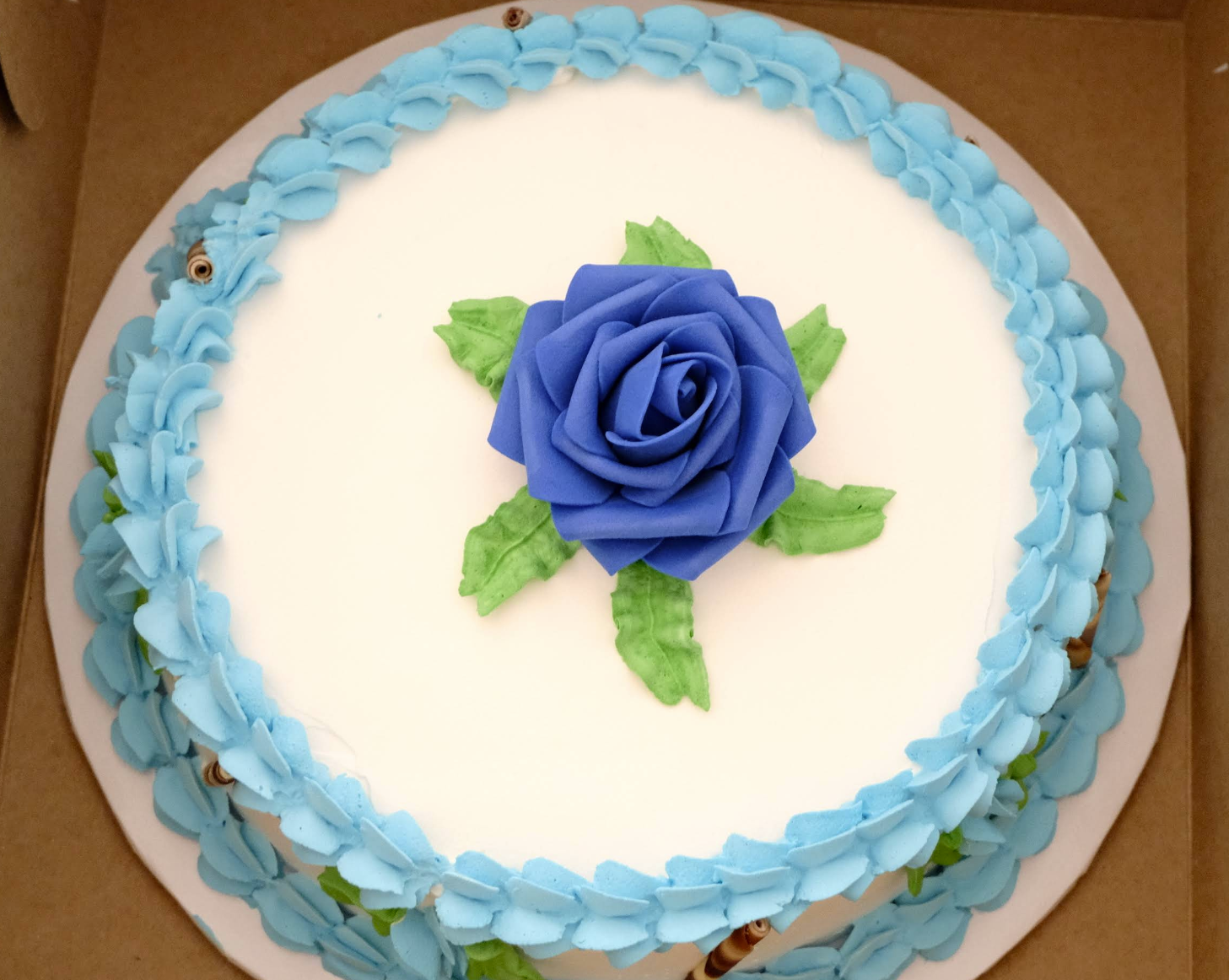 Decorated celebration cake from Gelateria Dolce Mia with blue icing flower