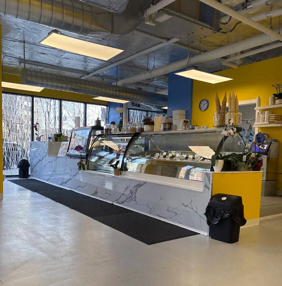 Inside Gelateria Dolce Mia with gelato counter, yellow walls and blue columns